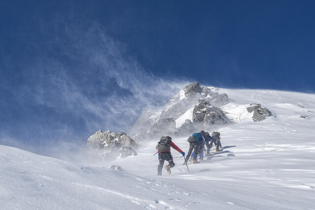 group of people climbing snow covered mountains