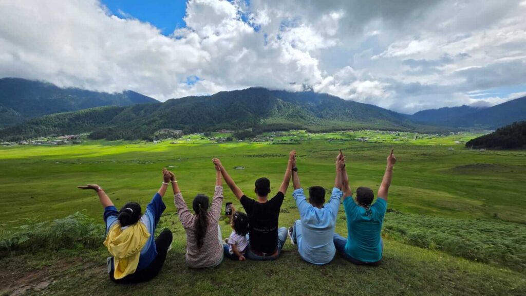 Group of travelers with raised hands enjoying the Bhutan valley view.