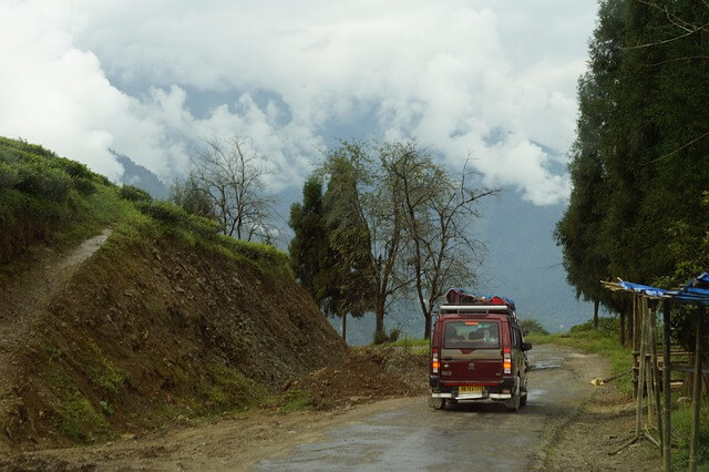SUV with luggage driving on a misty mountain road.
