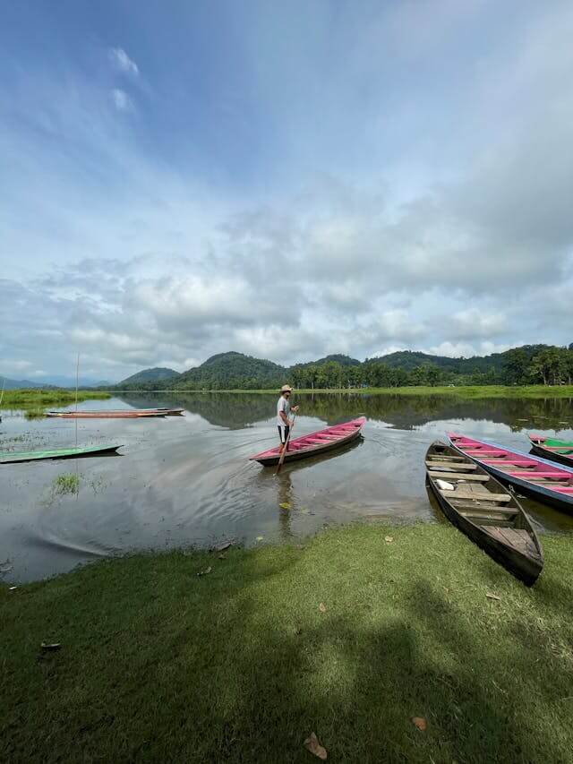 A person boating on a river in Assam surrounded by greenery.
