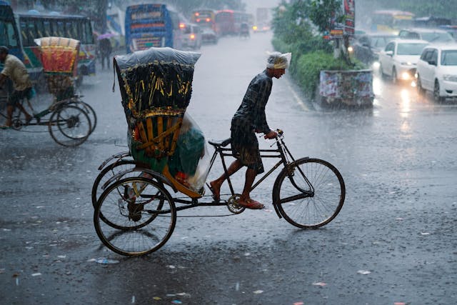 Cycle rickshaw moving through rainy street in Assam